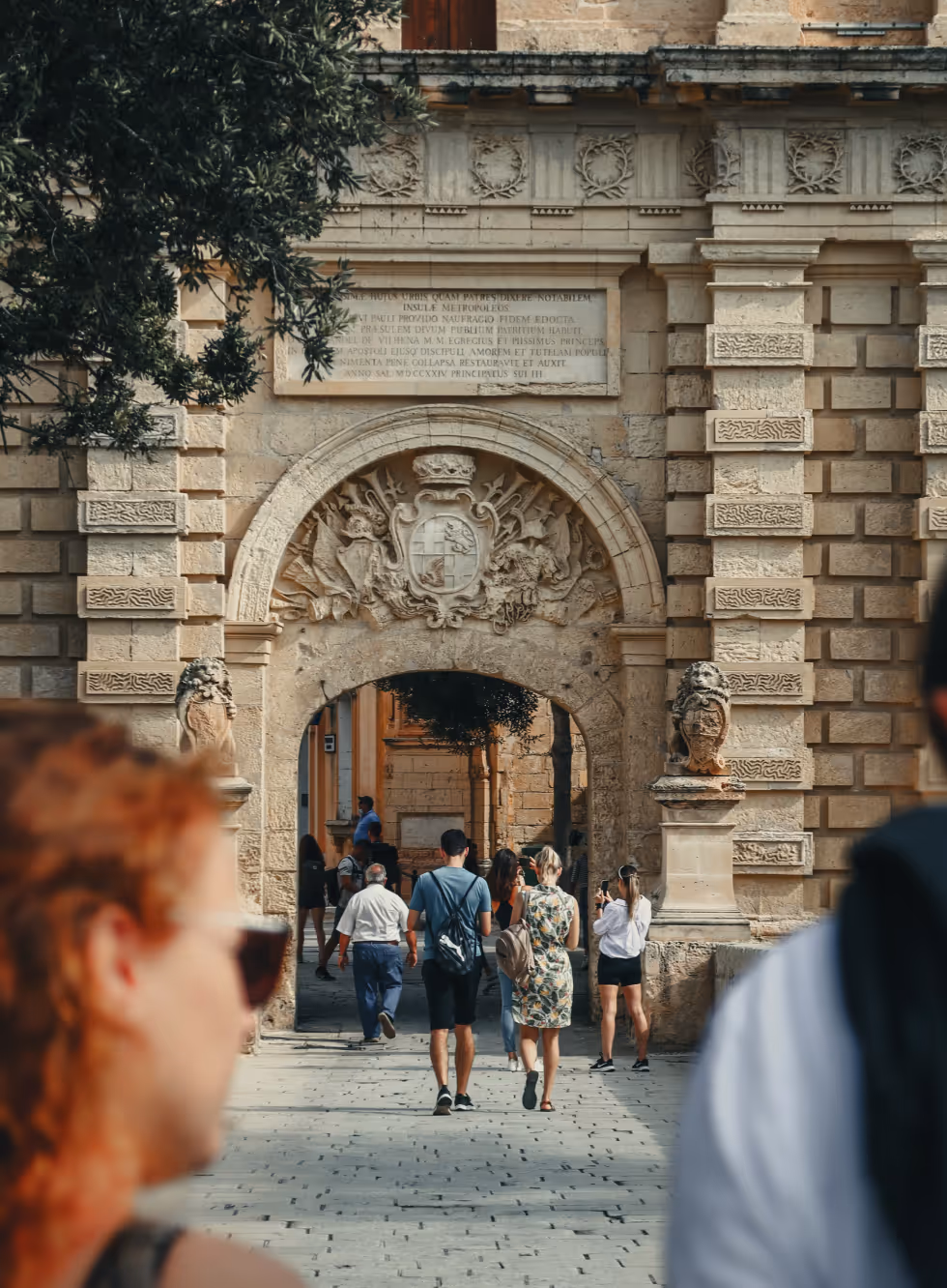 Street-level photograph through a large stone arched gateway in an old European city